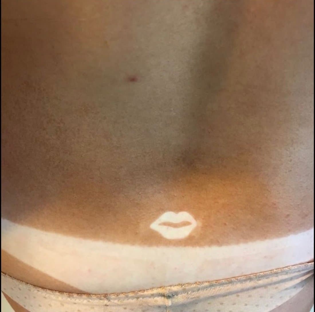 A real client's back with a cute lipstick-kiss design left in the spray tan